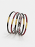 Five stacked bangles with a textured black and silver outer layer and a central gold band inlaid with red stones, UGA Color-Filled Bracelet Set