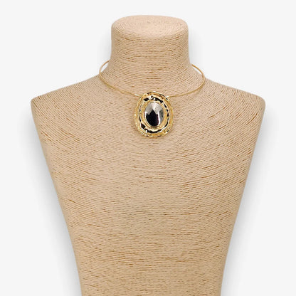 Gold necklace with a large pendant on a mannequin bust against a white background