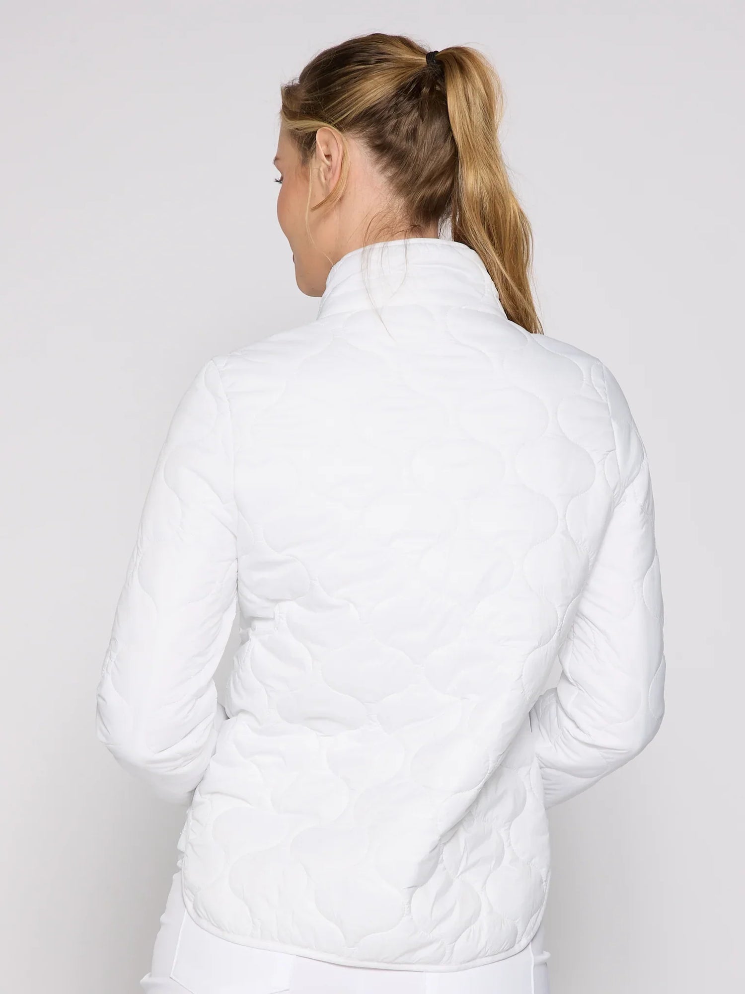 Person wearing a white quilted jacket on a plain background