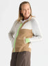 A woman modeling a color-blocked zip-up hoodie sweater with a tan body, light gray sleeves, white shoulder panels, and light green zipper and pocket accents, against a plain light gray background.