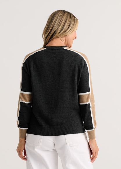 A woman viewed from the back wearing a black knit sweater with beige and white color-blocked shoulder and sleeve stripes Zaket &amp; Plover Block Play Sweater