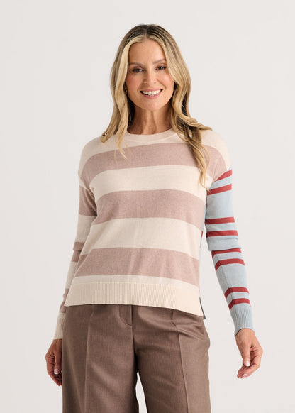 A woman modeling a long-sleeve knit sweater with horizontal stripes in dusty pink, cream, and light blue, featuring red stripes on the right sleeve Zaket &amp; Plover Bold Stripe Sweater Waxpaper 