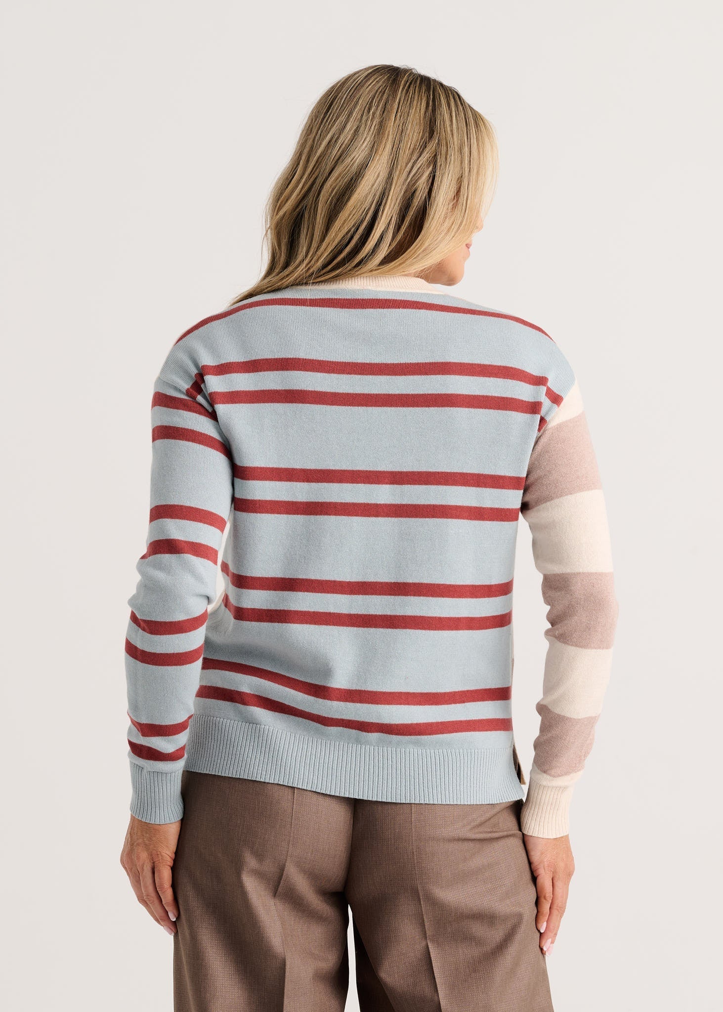 A woman viewed from the back wearing a light blue knit sweater with horizontal red and white stripes, plus beige color-blocked sleeves Zaket &amp; Plover Bold Stripe Sweater Waxpaper 