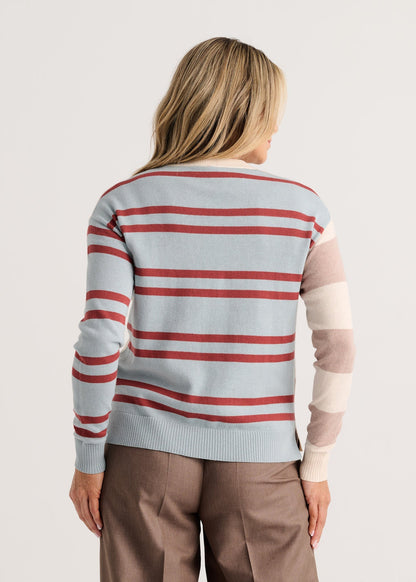 A woman viewed from the back wearing a light blue knit sweater with horizontal red and white stripes, plus beige color-blocked sleeves Zaket &amp; Plover Bold Stripe Sweater Waxpaper 