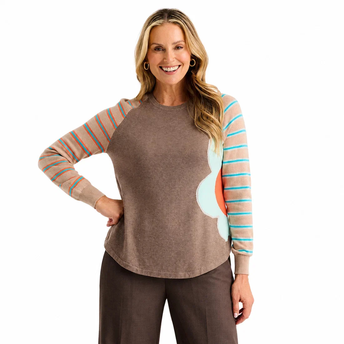 A woman modeling a long-sleeve crewneck top with a solid brown body, peach and turquoise striped sleeves, and a large light blue and coral abstract flower on the right side Zaket &amp; Plover Walnut Bright Side Sweater