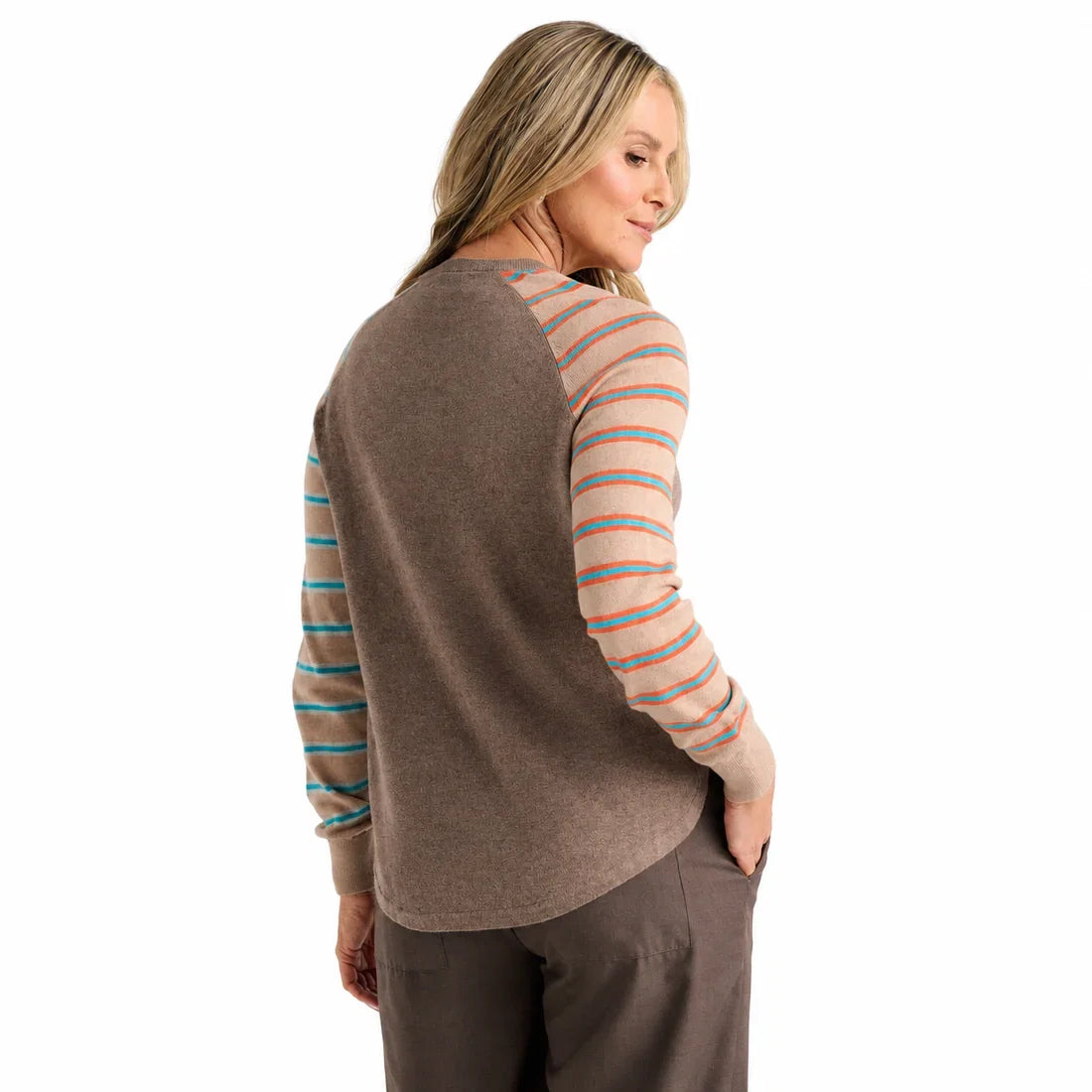 A woman modeling a long-sleeve crewneck top with a solid brown body, peach and turquoise striped sleeves, and a large light blue and coral abstract flower on the right side Zaket &amp; Plover Walnut Bright Side Sweater