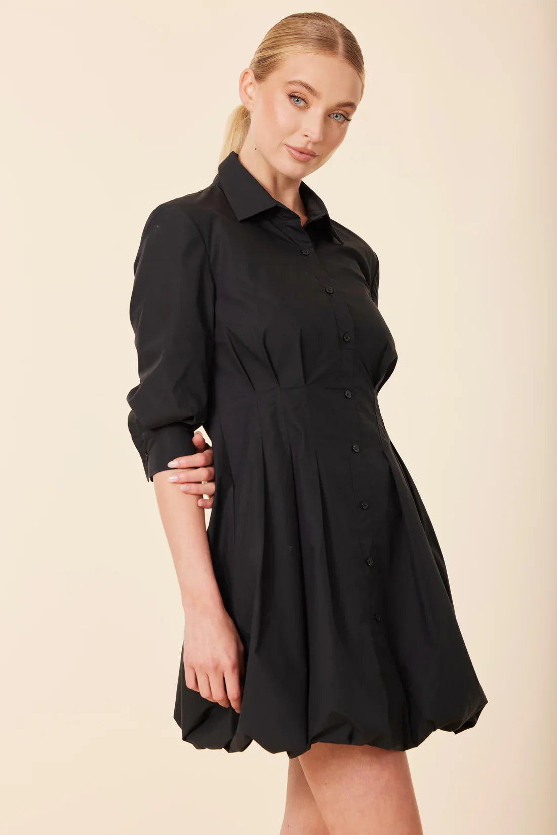 Woman wearing a black dress against a beige background