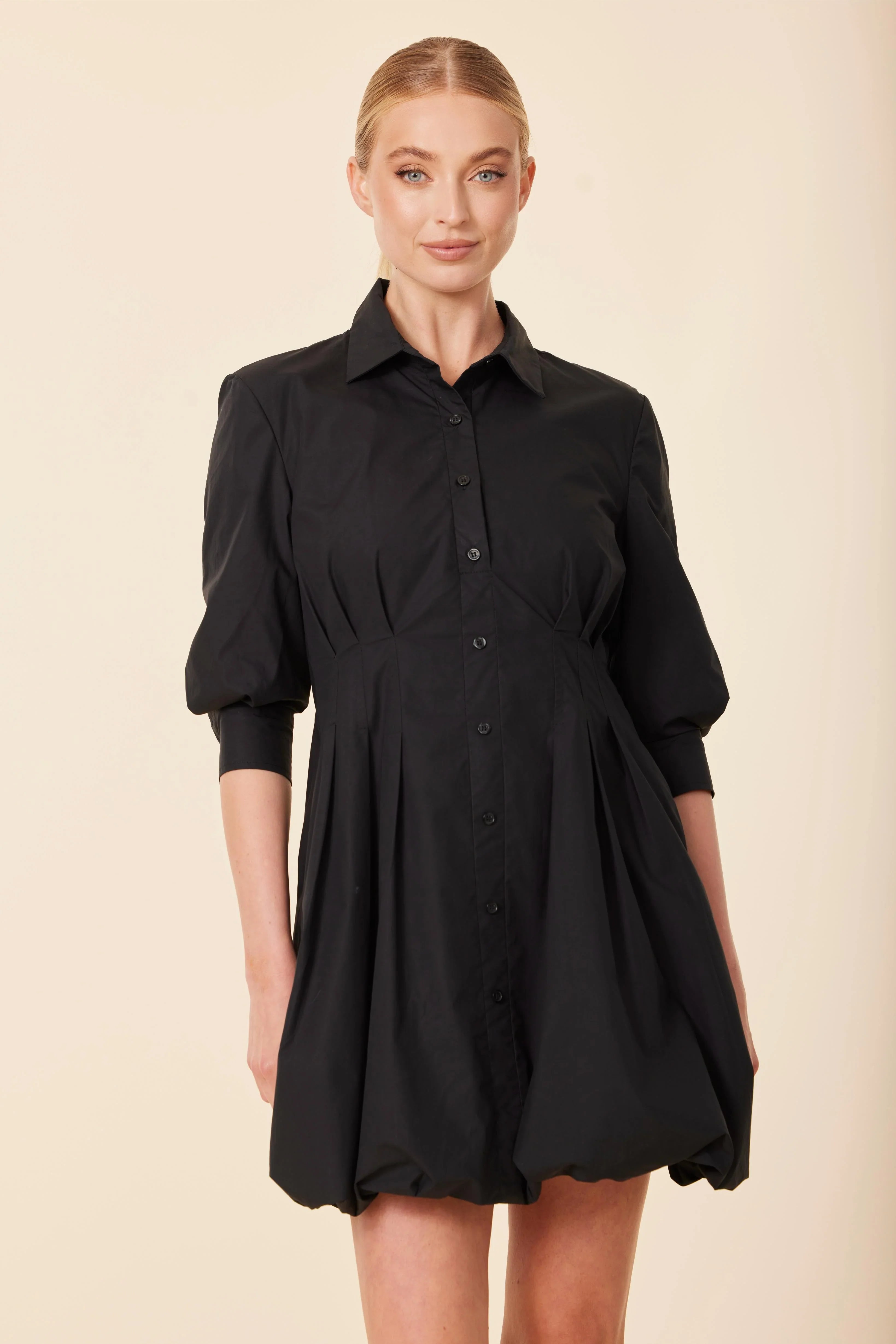 Woman wearing a black dress against a beige background