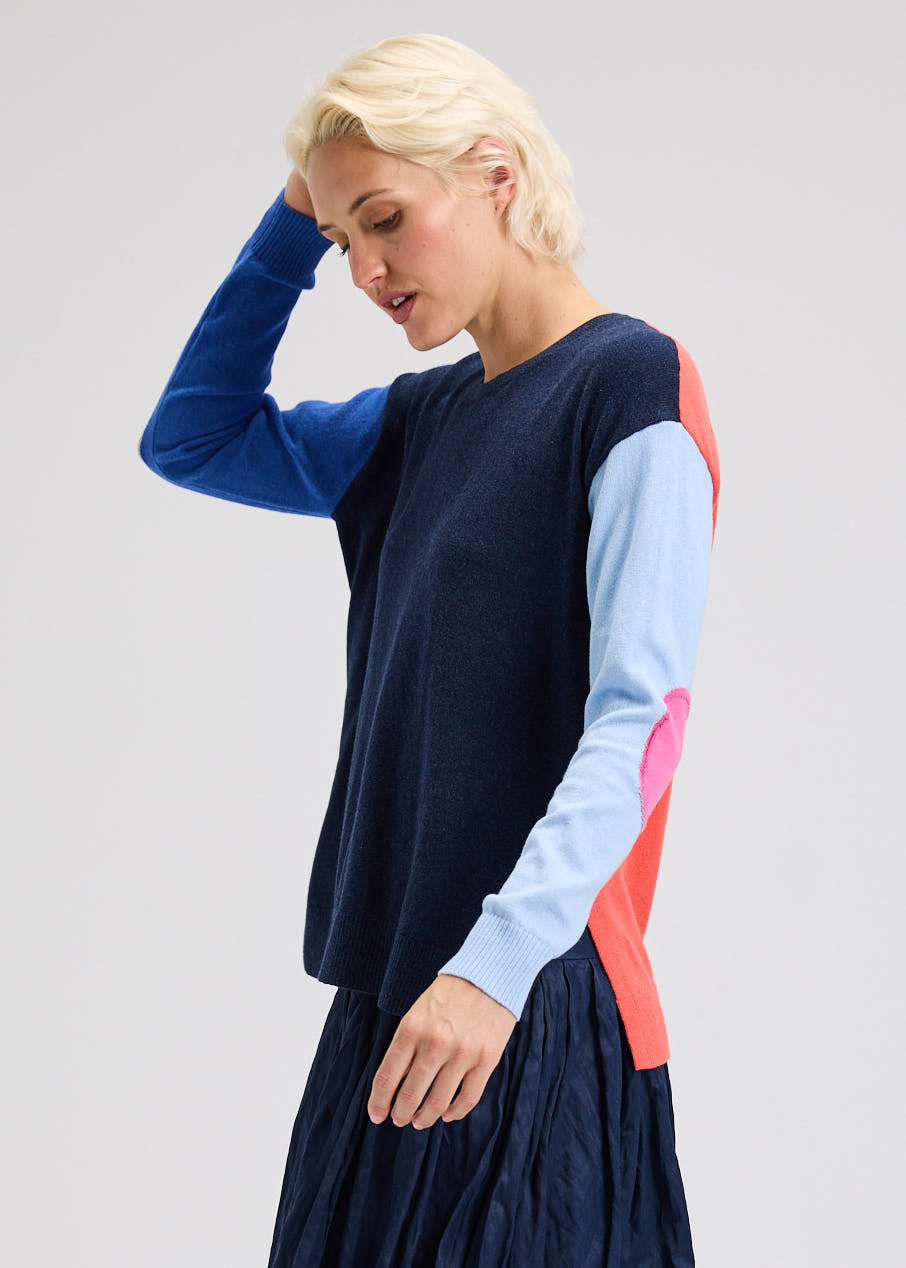 Woman wearing a long-sleeve dress with color-blocked sleeves on a plain background