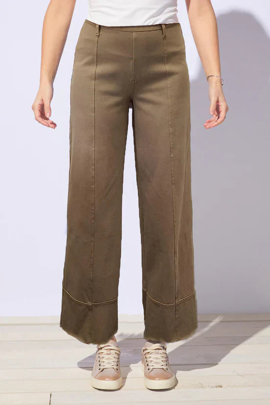 Person wearing brown, rust wide-leg jeans with a white background