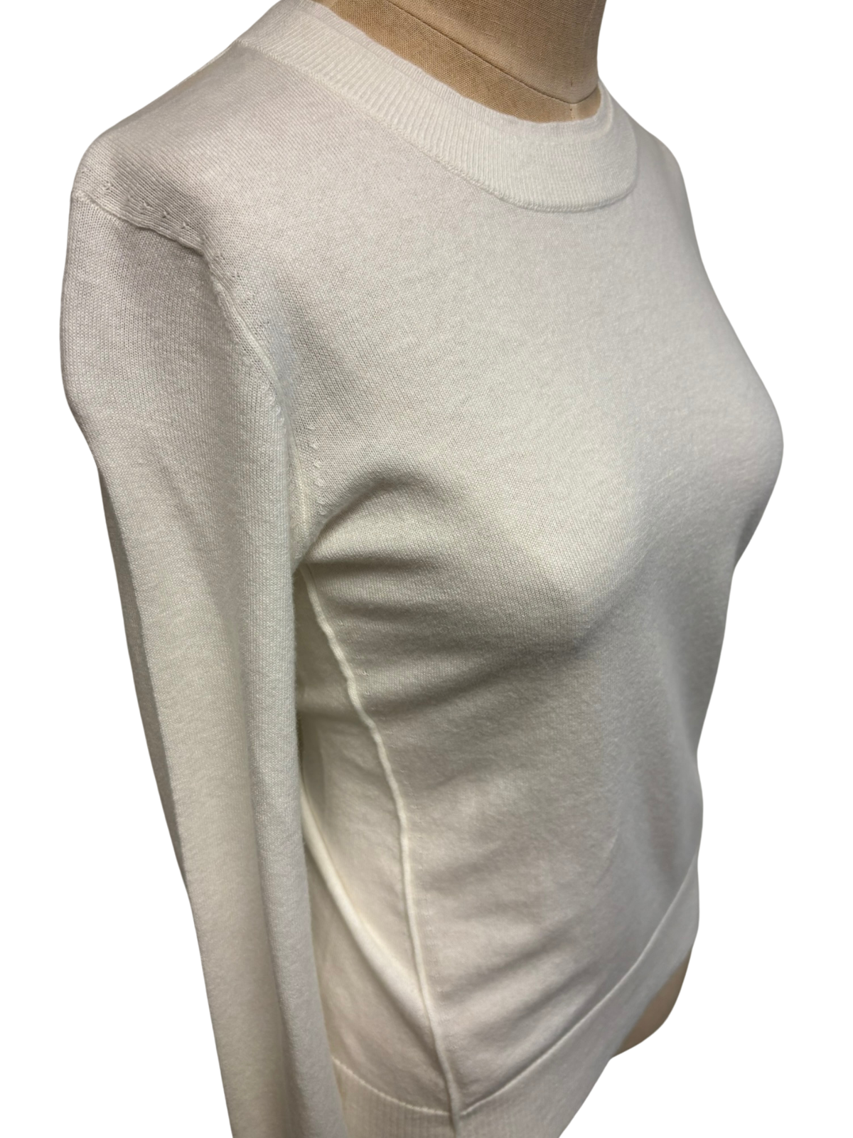 Close-up of PUREAMICI crew neck sweater showing soft knit fabric and classic design on a plain background.