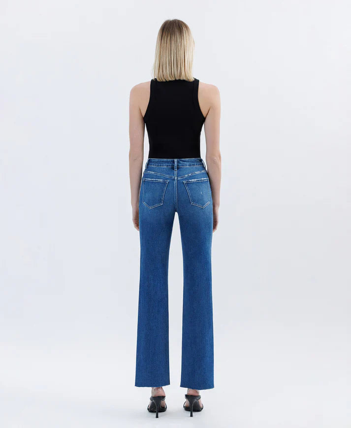 Person wearing blue jeans and a black top on a white background