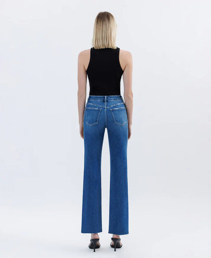 Person wearing blue jeans and a black top on a white background