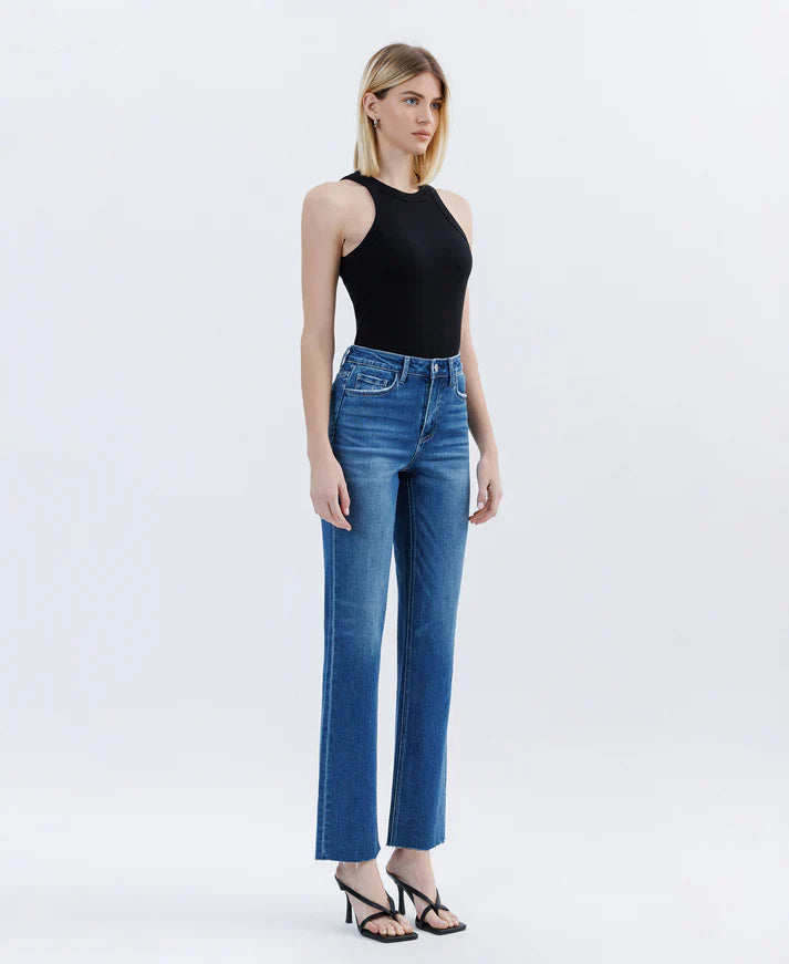 Woman wearing blue jeans and a black top on a white background