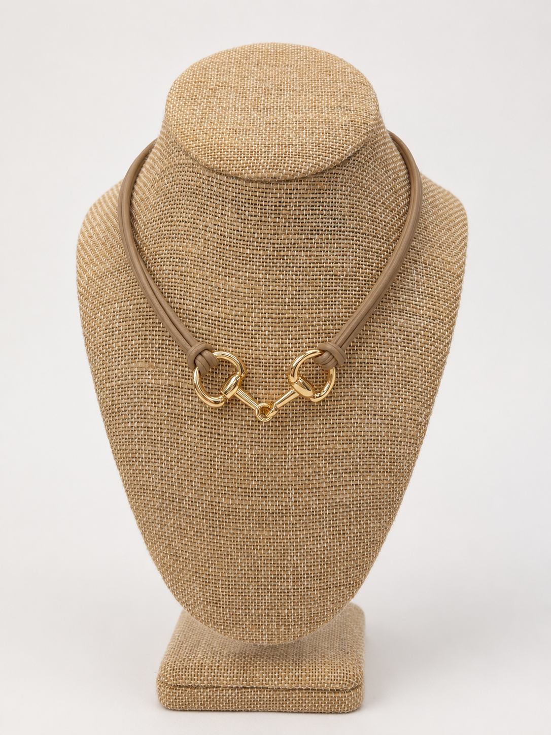 A gold horsebit-style clasp tan rope necklace 