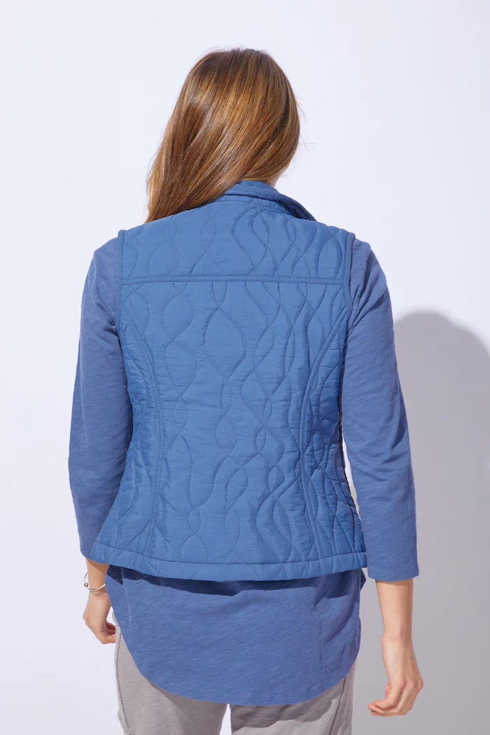 Woman wearing a blue quilted vest against a white background