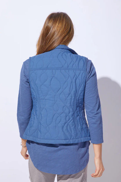 Woman wearing a blue quilted vest against a white background