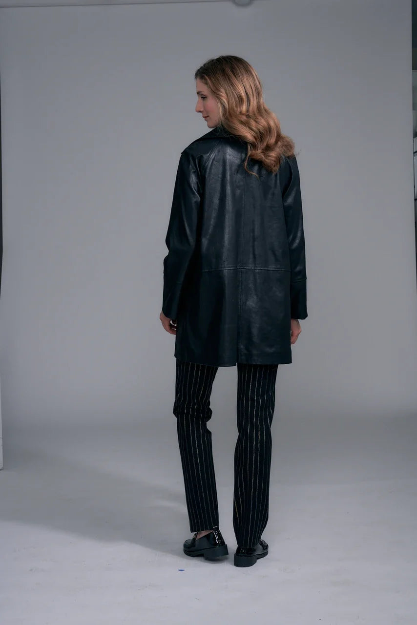 A woman modeling a black leather coat with gold-tone buttons by insight Vegan Leather Car Coat