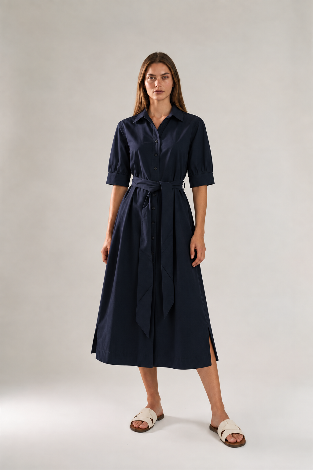A woman modeling a dark navy midi shirt dress with short sleeves, a button-up front, and a matching self-tie belt.