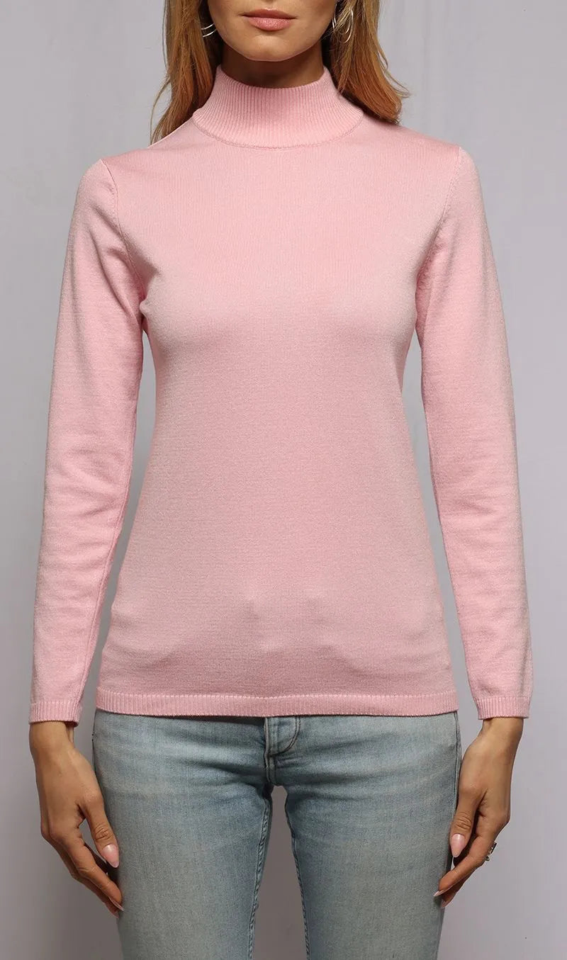 Person wearing a pink turtleneck sweater and light blue jeans on a gray background