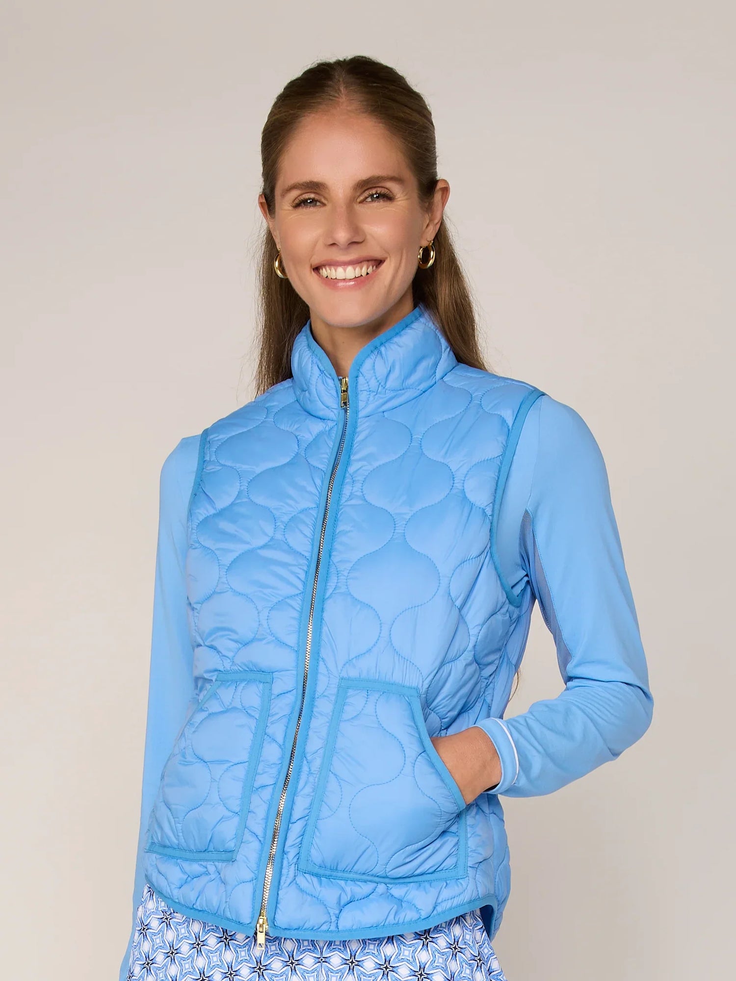 Woman wearing a blue quilted jacket against a plain background