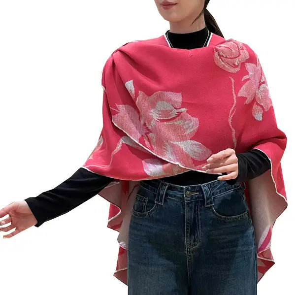 Person wearing a pink floral poncho over a black long-sleeve shirt and blue jeans on a white background