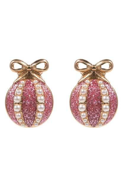 Pink glittery christmas earrings with pearl accents and gold bows on a white background