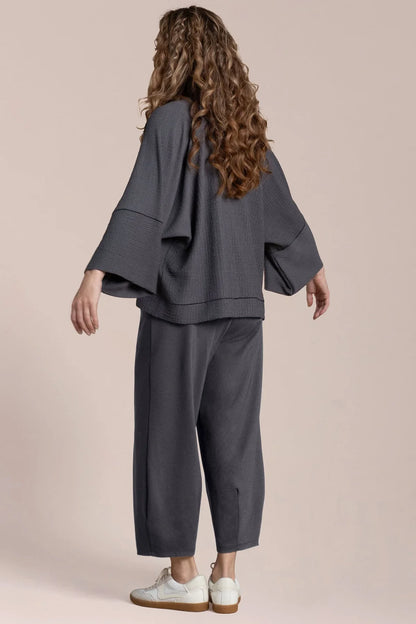 Person wearing a gray outfit with white shoes on a beige background