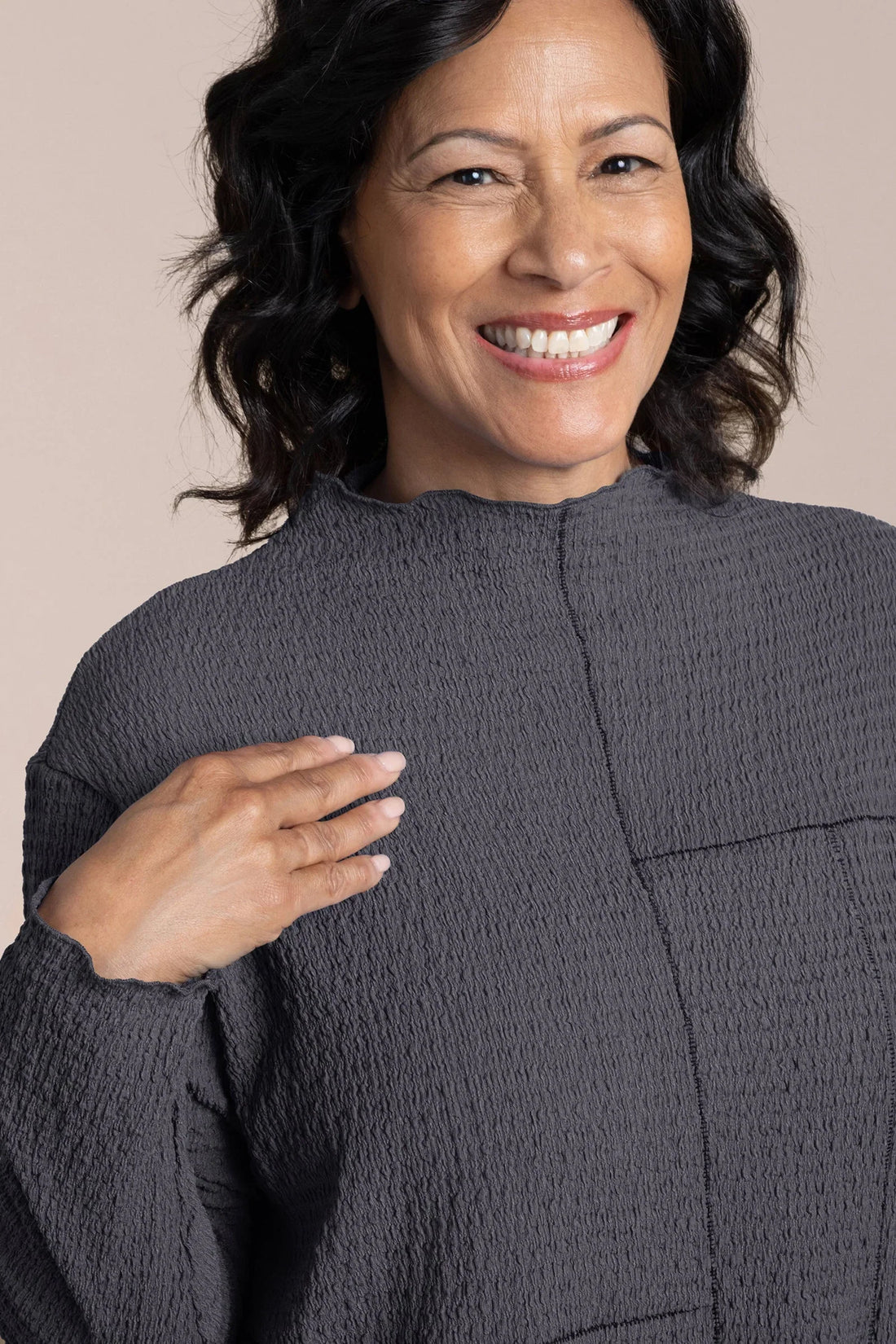 Woman wearing a textured gray sweater against a beige background