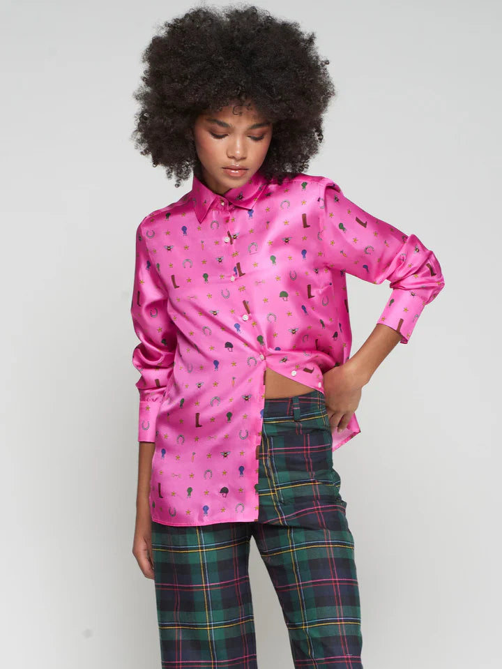 Person wearing a bright pink shirt with a equestrian pattern and plaid pants on a plain background