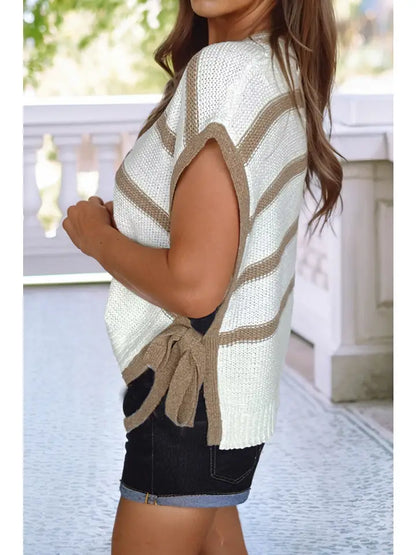 Woman wearing a white and beige striped sleeveless top with a tie detail, standing outdoors.