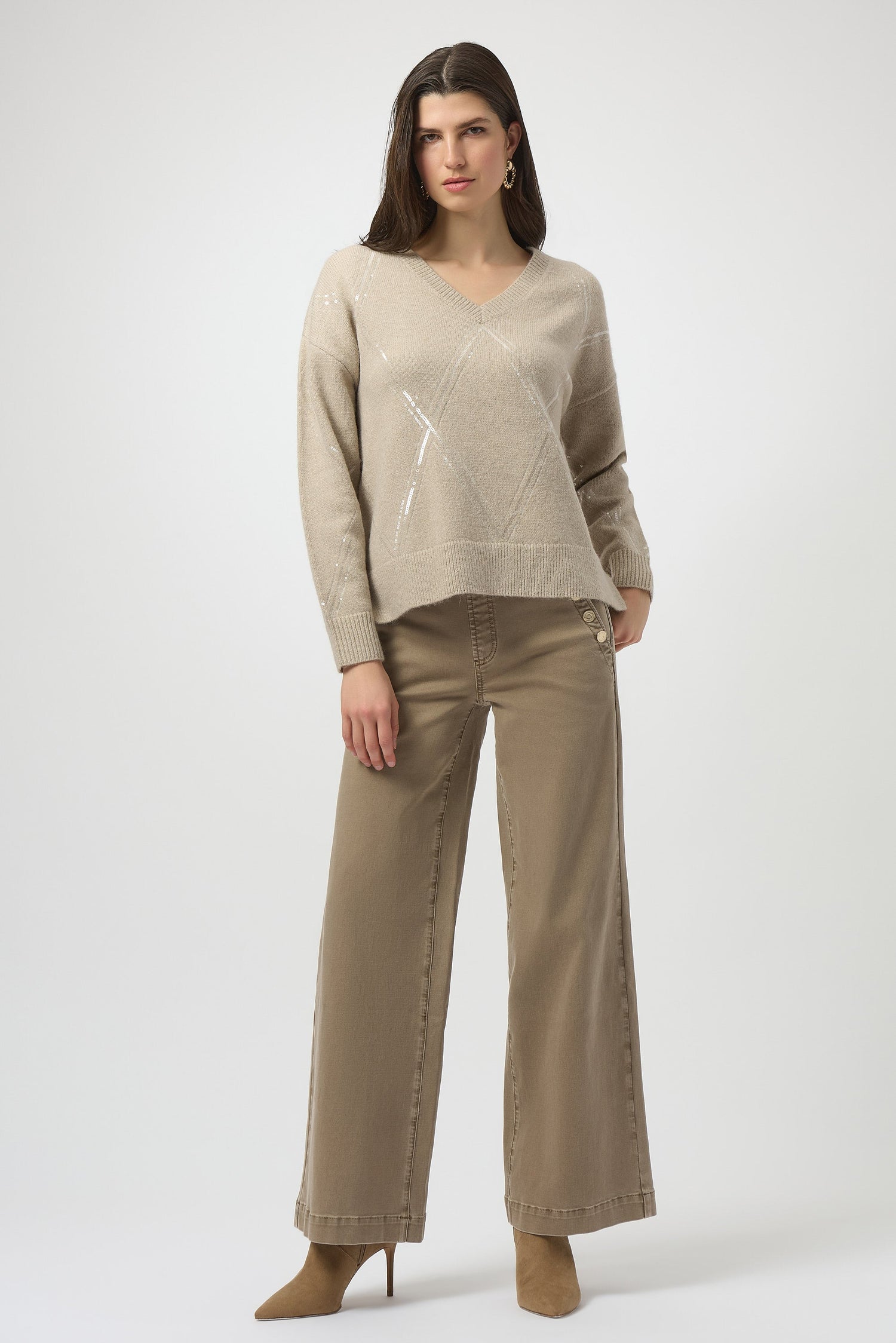 Woman wearing a beige sweater and pants on a white background
