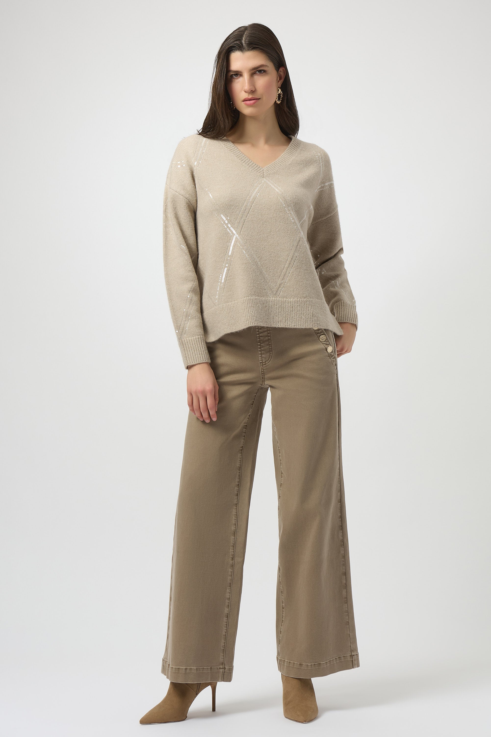 Woman wearing a beige sweater and pants on a white background