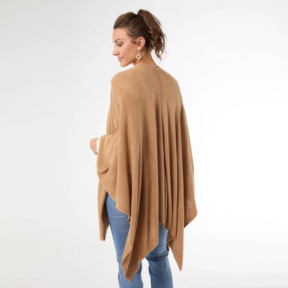 Woman wearing a beige poncho over a white background