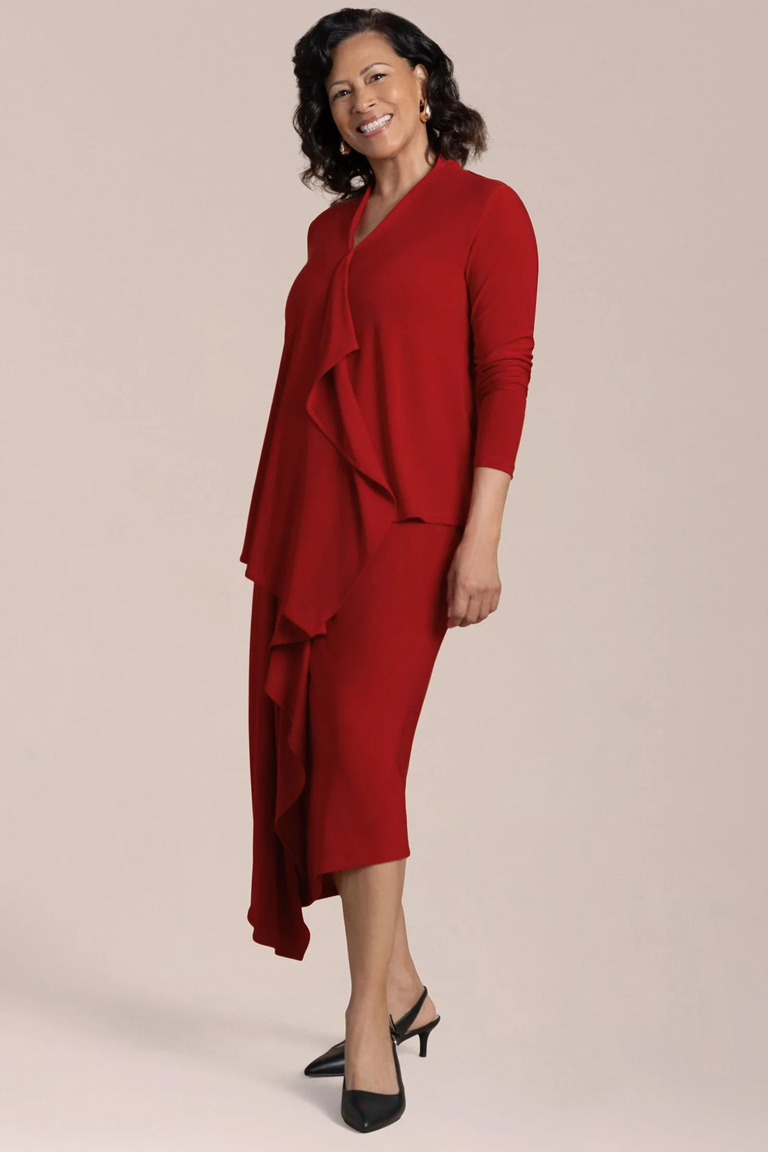 Woman wearing a red dress with a ruffled design on a beige background