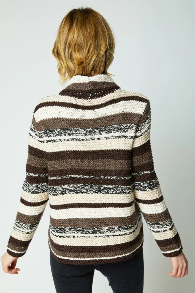 Person wearing a brown and beige striped sweater on a plain background