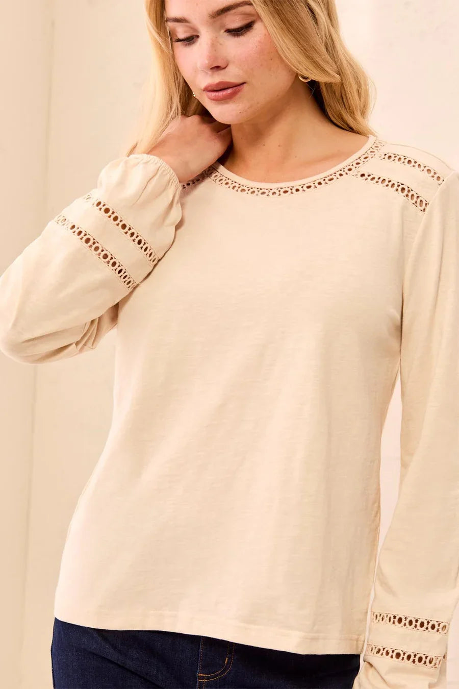 A woman wearing a light cream long-sleeve top with decorative eyelet lace detailing at the neckline and cuffs by tribal Cotton Slub Eyelet Trim Long Sleeve Knit Top