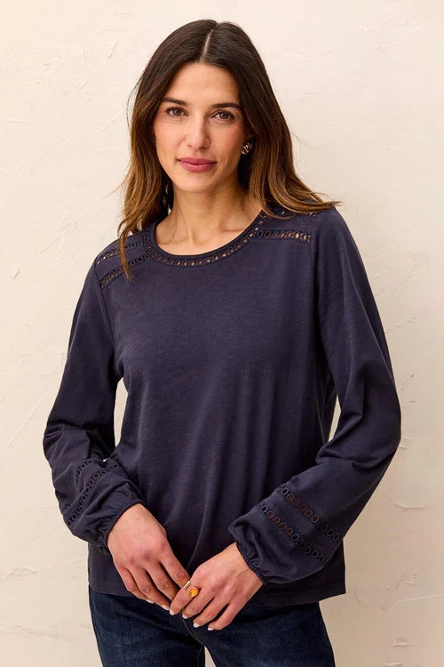 A woman wearing a dark navy blue long-sleeve top with decorative eyelet lace detailing at the neckline and cuffs by tribal Cotton Slub Eyelet Trim Long Sleeve Knit Top