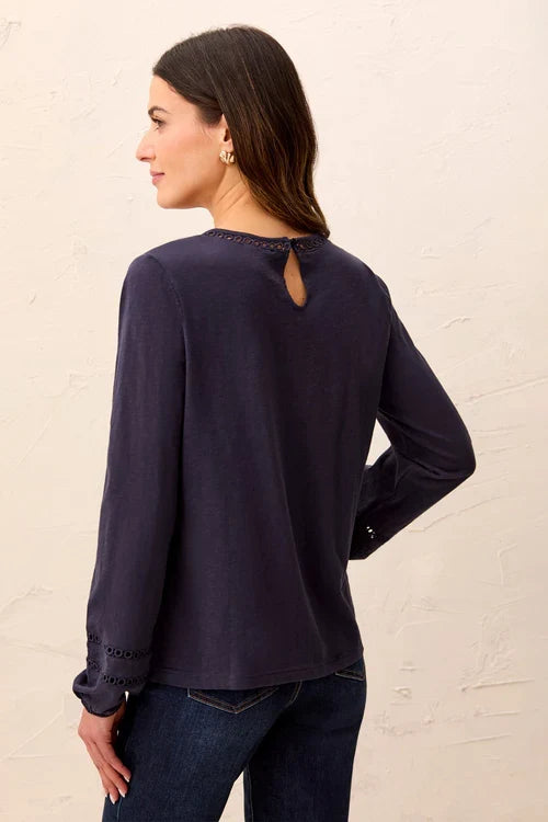 A woman wearing a dark navy blue long-sleeve top with decorative eyelet lace detailing at the neckline and cuffs by tribal Cotton Slub Eyelet Trim Long Sleeve Knit Top