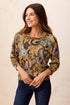 A woman wearing a long-sleeve crewneck top with an intricate paisley and floral pattern in gold, blue, green, and brown by tribal Soft Yarn Three-Quarter Sleeve Crewneck Sweater