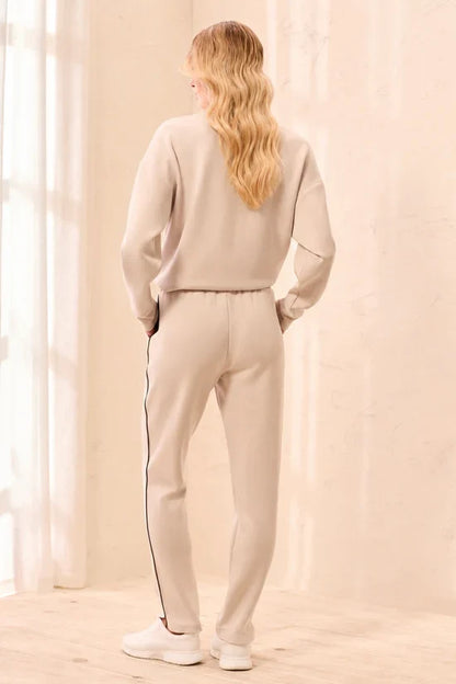 A woman modeling straight-leg pants, featuring thin black side stripes by tribal TECHNO LUX Jogger Pants With Contrast Piping And U-Hem