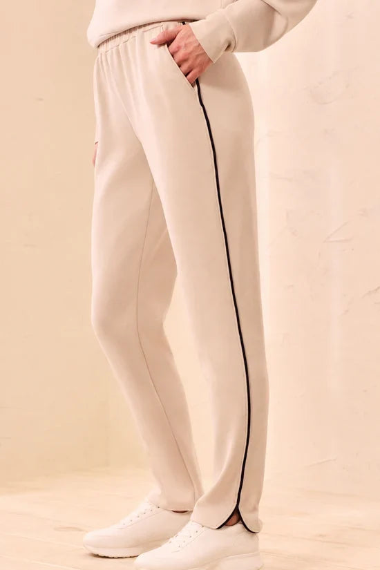 A woman modeling straight-leg pants, featuring thin black side stripes by tribal TECHNO LUX Jogger Pants With Contrast Piping And U-Hem