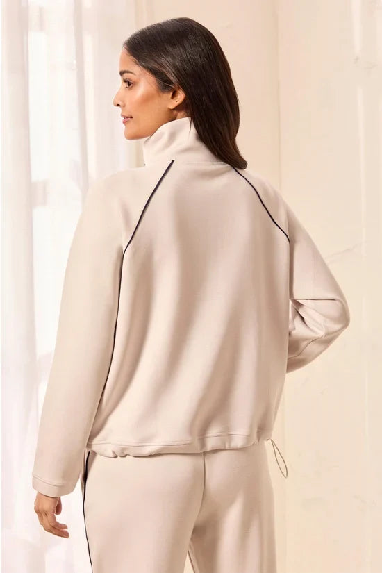 A woman modeling a matching beige tracksuit with a half-zip pullover and straight-leg pants, featuring thin black side stripes by tribal TECHNO LUX Pop Over Quarter Zip Pullover